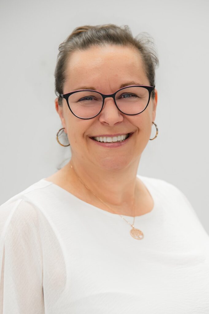 Jasmin Walter, Therapeutin im Vitanium Therapiezentrum Pro, mit Brille und weißem Oberteil, freundlicher Blick in die Kamera.