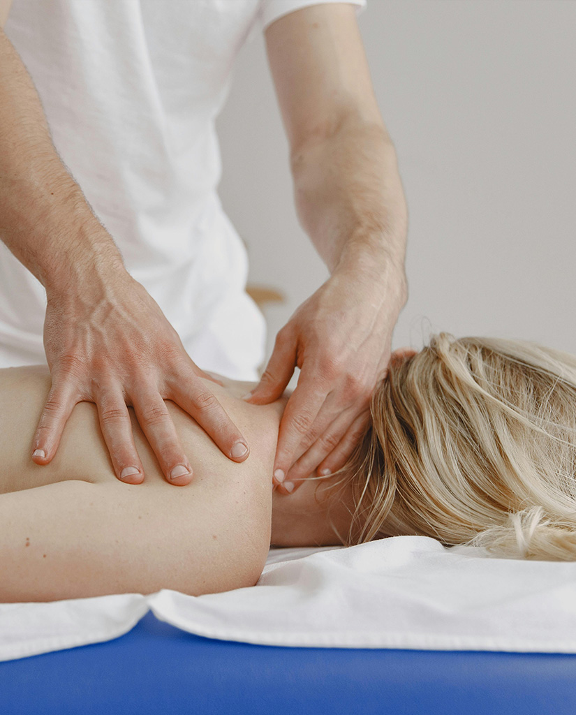 Therapeut massiert die Schulter- und Nackenpartie einer liegenden Patientin im Therapiezentrum Vitanium Health Solutions