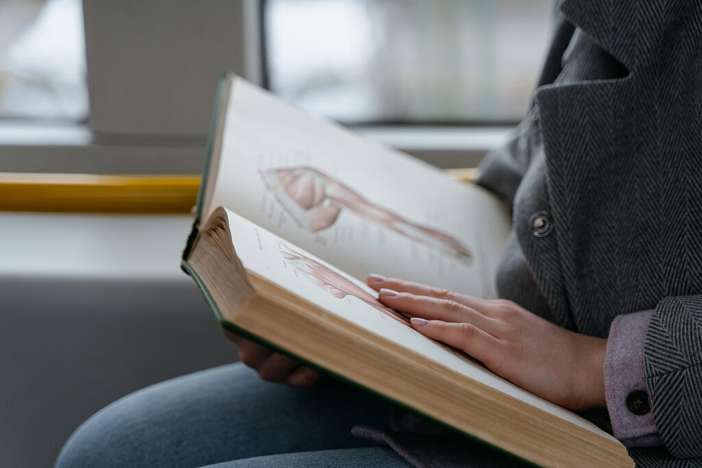 Person liest ein anatomisches Lehrbuch in öffentlichen Verkehrsmitteln – Vitanium Health Solutions Ausbildung