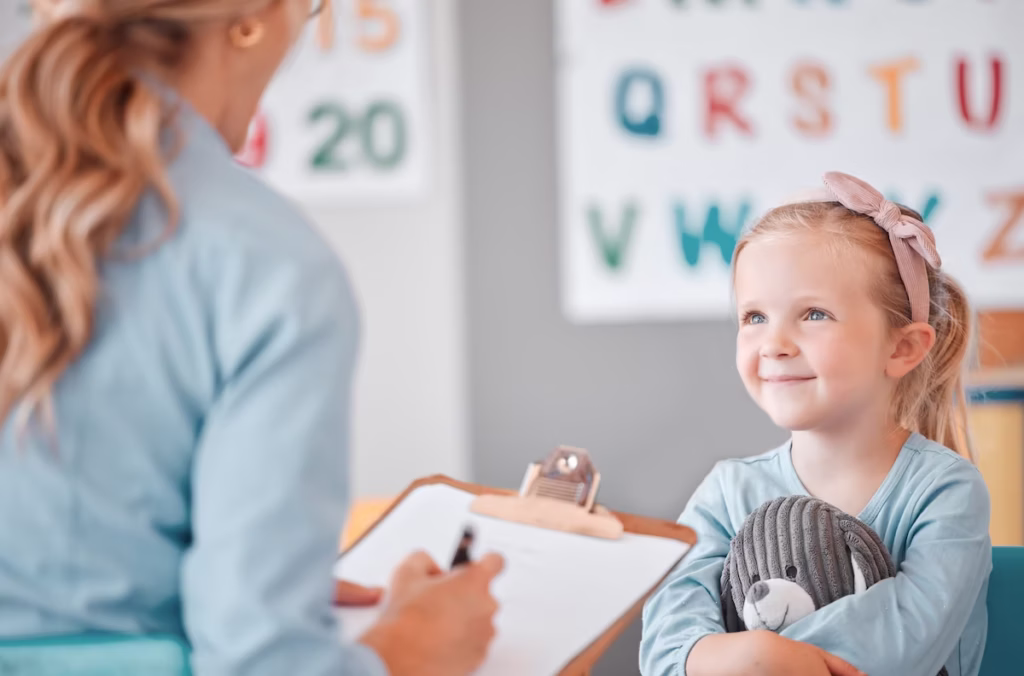 Kleines Mädchen mit Stofftier lächelt beim psychologischen Diagnostikgespräch im Therapiezentrum Pro